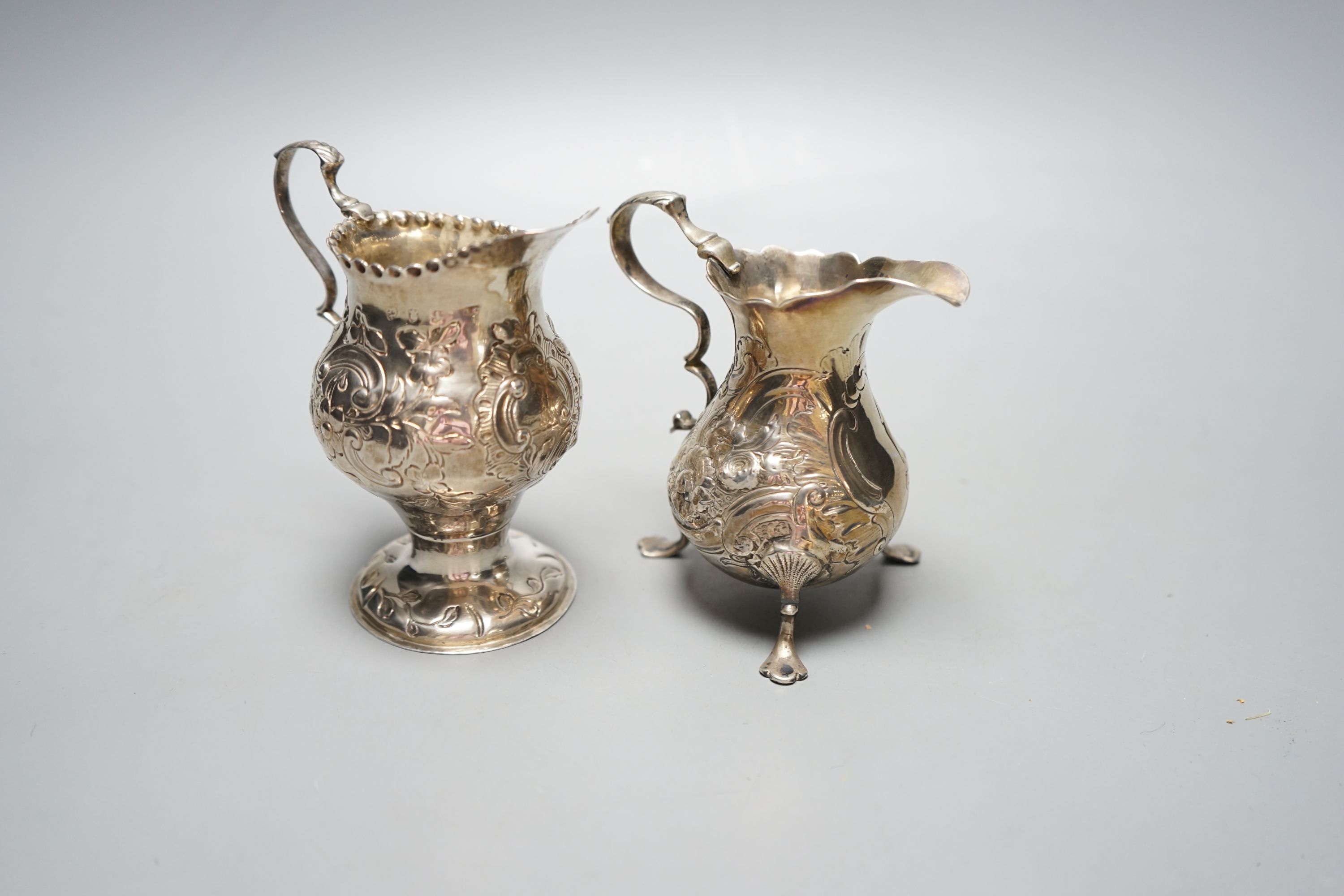 Two 18th century silver cream jugs, with later embossed decoration, London, 1753 & London, 1770, tallest 10.6cm, 174 grams.